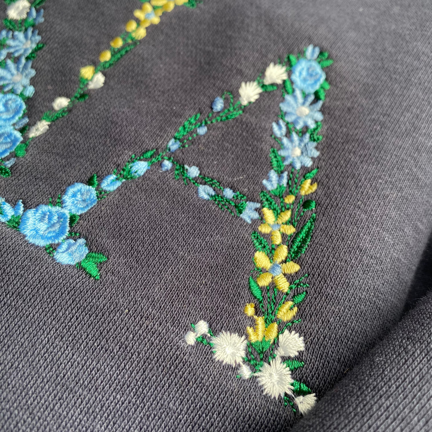 Mẫu thêu áo sweater chữ hoa NANA trên áo nỉ xanh navy, món quà ý nghĩa dành cho người phụ nữ tuyệt vời nhất